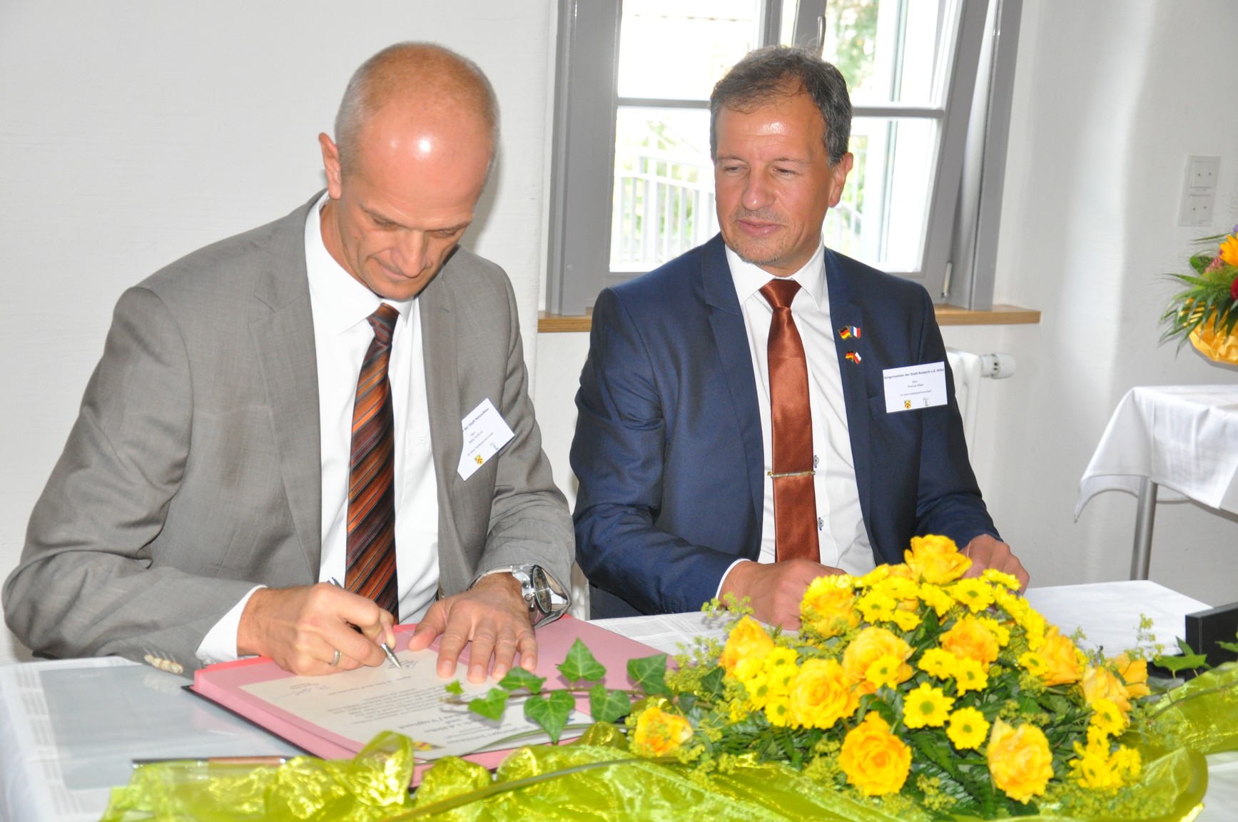 Bürgermeister Thomas Alber (rechts) und Mike Purfürst (links) beim unterzeichnen der Urkunde.